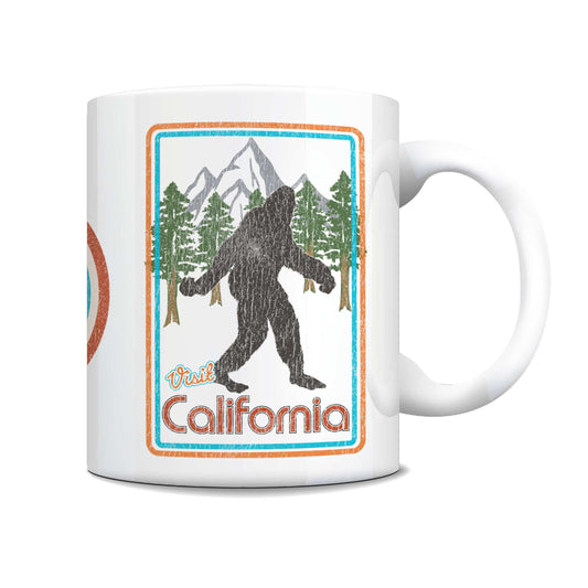 A white ceramic coffee mug featuring a retro-style California Bigfoot graphic with mountains, pine trees, and the text 'Paul California' in orange and blue.