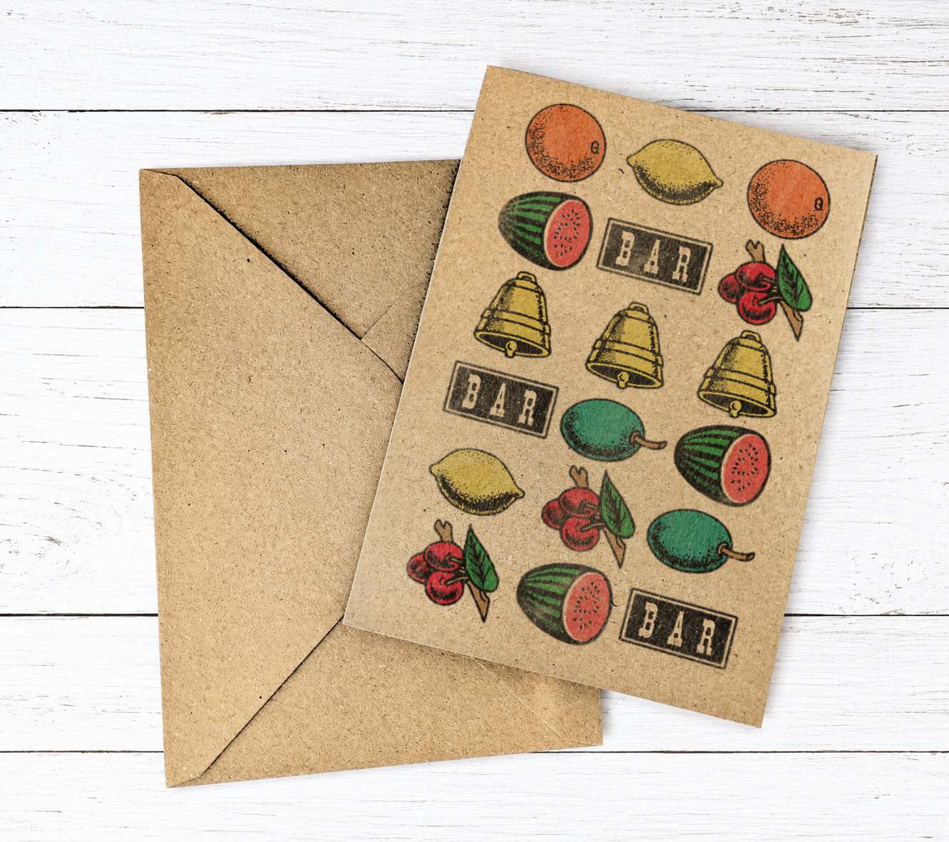 A kraft paper greeting card with vintage-style fruit slot machine logos illustrations of lemons, watermelons, bells, cherries, and the word 'BAR' repeated, shown with a matching kraft envelope on a white wood background.