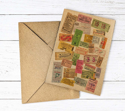 A square kraft paper card printed with a collage of vintage travel ticket illustrations, shown with a matching brown envelope on a white wood plank background.
