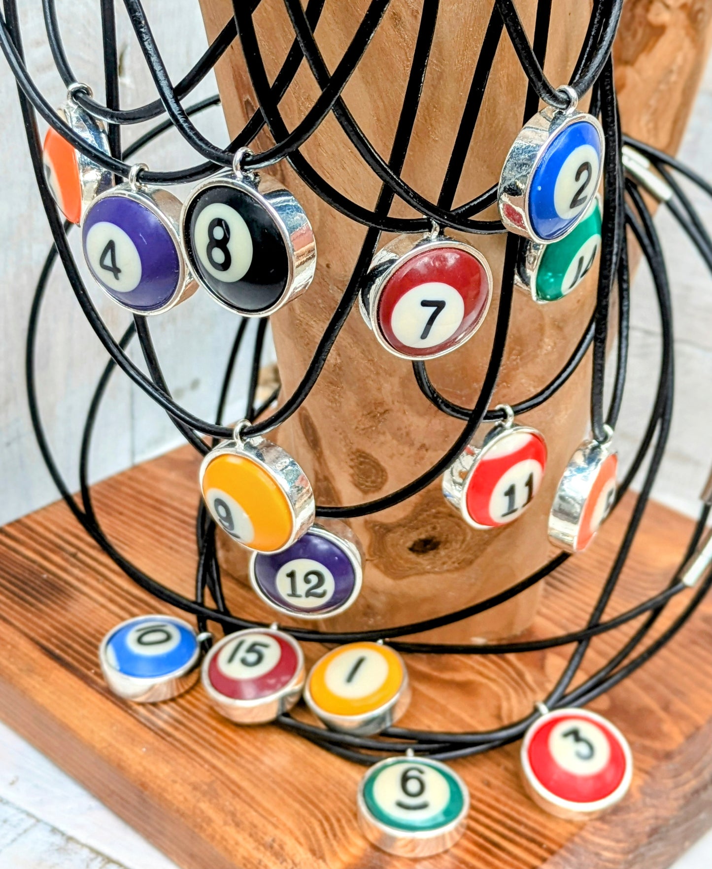 Set of billiard ball charm necklaces on a wooden stand